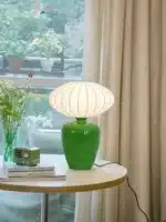 Vintage table lamp with retro ceramic base and silk shade on bedside table in cozy bedroom