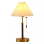 Retro desk lamp with black metal base and pleated fabric shade in warm glow