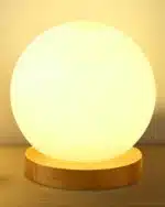 Modern table lamp with iron body and wood base illuminating a cozy bedroom