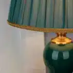 Green ceramic table lamp with European cloth shade in a modern living room setting