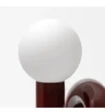 Modern glass table lamp with spherical shade on a wooden nightstand in a cozy bedroom