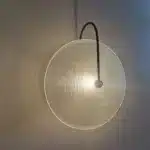 Modern wall lamp with minimalist Nordic design illuminating a cozy bedroom bedside