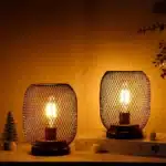 Battery table lamp with metal cage and warm LED glow on a wooden table