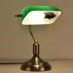 Antique bronze table lamp with green shade on bedside table
