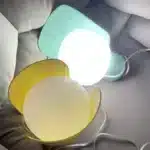 Rotating petal desk lamp with adjustable petals in pastel colors on a bedside table