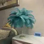 Ostrich feather table lamp glowing warmly on a bedside table in a cozy bedroom
