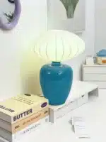Vintage table lamp with retro ceramic base and silk shade on bedside table in cozy bedroom