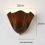 Modern wall sconce with shell-shaped glass and LED light in a minimalist living room