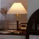 Retro desk lamp with black metal base and pleated fabric shade in warm glow