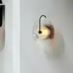 Modern wall lamp with minimalist Nordic design illuminating a cozy bedroom bedside