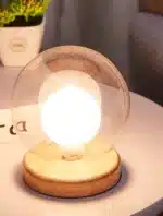 Modern table lamp with iron body and wood base illuminating a cozy bedroom