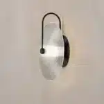 Modern wall lamp with minimalist Nordic design illuminating a cozy bedroom bedside