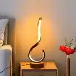 Modern desk lamp with adjustable arm and USB cable, glowing warmly on a wooden desk