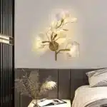 Luxury gold leaf sconce with modern ginkgo design illuminating a living room wall