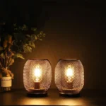 Battery table lamp with metal cage and warm LED glow on a wooden table