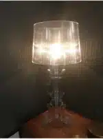 Modern acrylic table lamp glowing softly on a bedside table in a contemporary bedroom