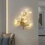 Luxury gold leaf sconce with modern ginkgo design illuminating a living room wall