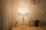 White ghost table lamp with transparent baroque design on a bedside table in a modern bedroom