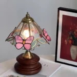 Vintage desk lamp with stained glass butterfly shade casting warm glow on bedside table