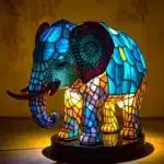 Colorful stained glass animal lamp featuring a cat design, glowing warmly on a bedside table
