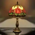 Tiffany table lamp with tulip stained glass shade, rustic bronze base, glowing warmly
