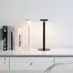 Modern rechargeable table lamp glowing warmly on a wooden bedside table