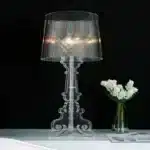 White ghost table lamp with transparent baroque design on a bedside table in a modern bedroom
