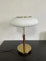 White glass table lamp with vintage design on a wooden desk in a cozy bedroom
