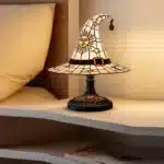 Witch hat lamp with stained glass pattern casting a warm glow on a bedside table