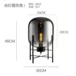Modern floor lamp with iron frame and glass shade in a cozy living room