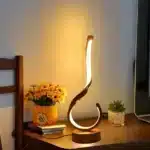 Modern desk lamp with adjustable arm and USB cable, glowing warmly on a wooden desk