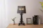 White ghost table lamp with transparent baroque design on a bedside table in a modern bedroom