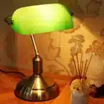 Antique bronze table lamp with green shade on bedside table