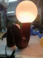 Modern glass table lamp with spherical shade on a wooden nightstand in a cozy bedroom