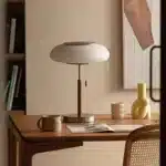 White glass table lamp with vintage design on a wooden desk in a cozy bedroom