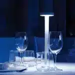 Modern rechargeable table lamp glowing warmly on a wooden bedside table