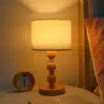 Vintage table lamp with fabric shade and solid wood base on bedside table
