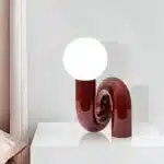 Modern glass table lamp with spherical shade on a wooden nightstand in a cozy bedroom