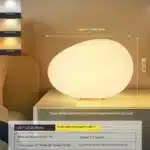 Warm night light pebble LED lamp glowing on a bedside table