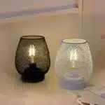 Decorative bird cage lamp with warm LED light, iron frame, and silk screen details on a bedside table
