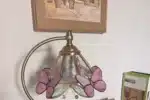 Vintage desk lamp with stained glass butterfly shade casting warm glow on bedside table