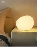 Warm night light pebble LED lamp glowing on a bedside table