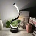 Modern desk lamp with adjustable arm and USB cable, glowing warmly on a wooden desk