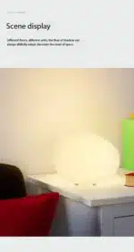 Warm night light pebble LED lamp glowing on a bedside table