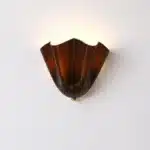Modern wall sconce with shell-shaped glass and LED light in a minimalist living room