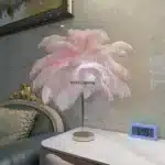 Ostrich feather table lamp glowing warmly on a bedside table in a cozy bedroom