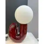Modern glass table lamp with spherical shade on a wooden nightstand in a cozy bedroom