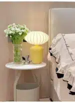 Vintage table lamp with retro ceramic base and silk shade on bedside table in cozy bedroom