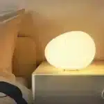 Warm night light pebble LED lamp glowing on a bedside table