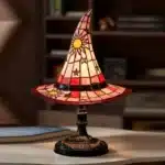 Witch hat lamp with stained glass pattern casting a warm glow on a bedside table
